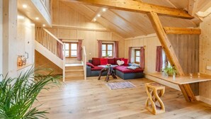 A wooden interior with a staircase, a red sofa, and a wooden table. - Five-star comfort vacation apartment Sternenstadl with balcony allergy-friendly (Rimsting)