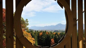 A circular wooden structure with a view of a forest and mountains in the background. - Five-star comfort vacation apartment Sternenstadl with balcony allergy-friendly (Rimsting)
