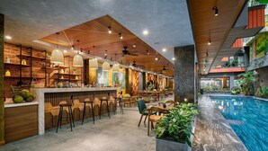 A modern bar area with wooden accents, seating, and a pool. - Chi House Danang (Da Nang)