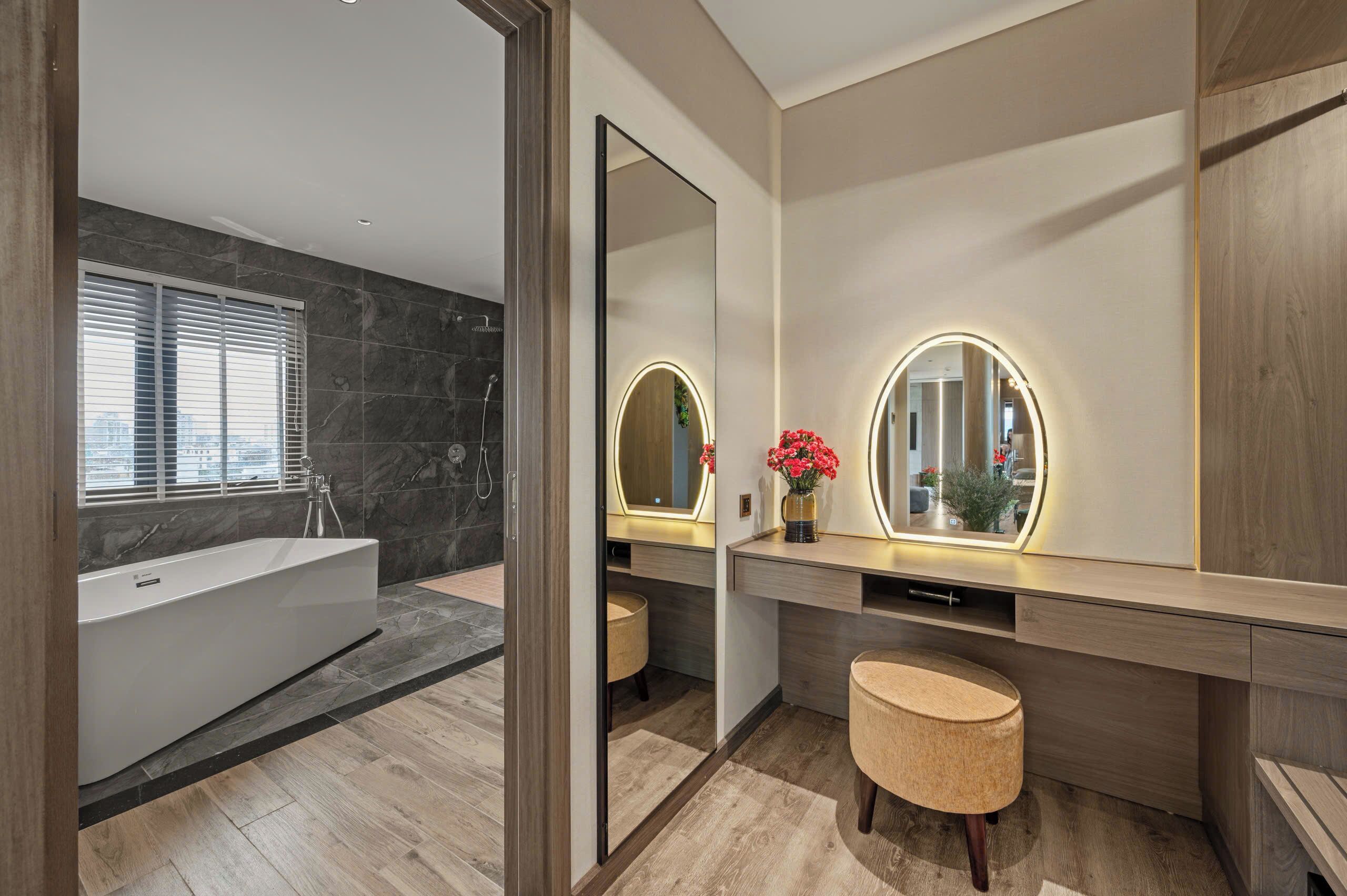 A modern bathroom with a large bathtub, two vanity mirrors with illuminated frames, and a wooden vanity.