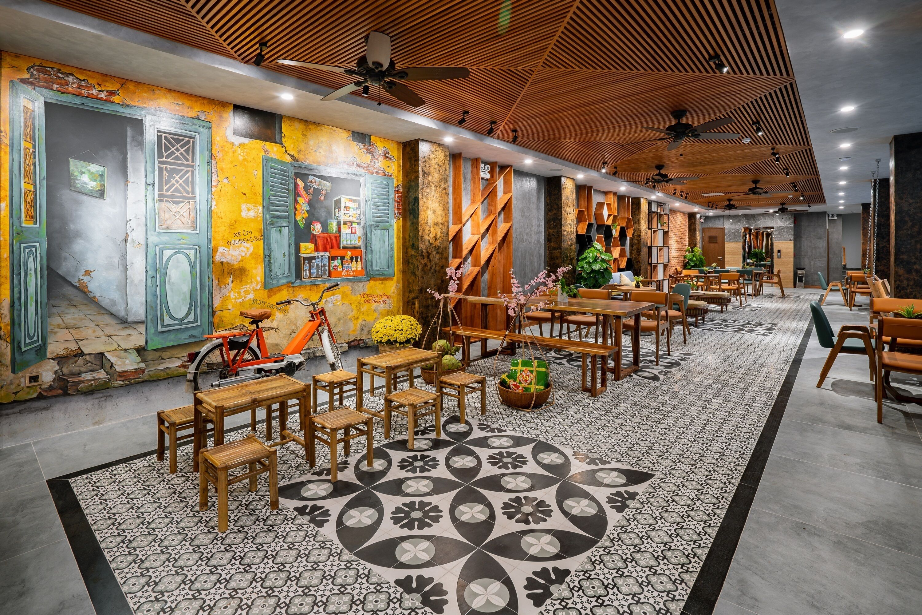 A spacious restaurant with wooden tables and chairs, a patterned floor, and a mural on the wall.