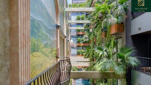 A multi-level atrium with a mural, indoor pool, and lush greenery. - Chi House Danang (Da Nang)