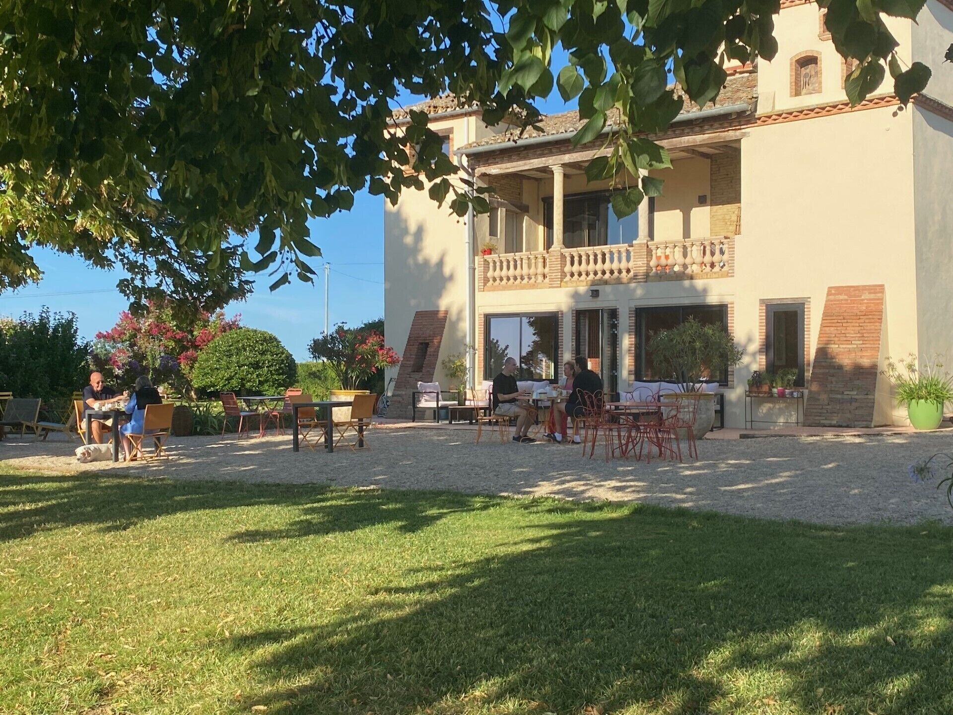 Ein Gebäude mit Balkon, Sitzgelegenheiten im Freien und einem Gartenbereich.