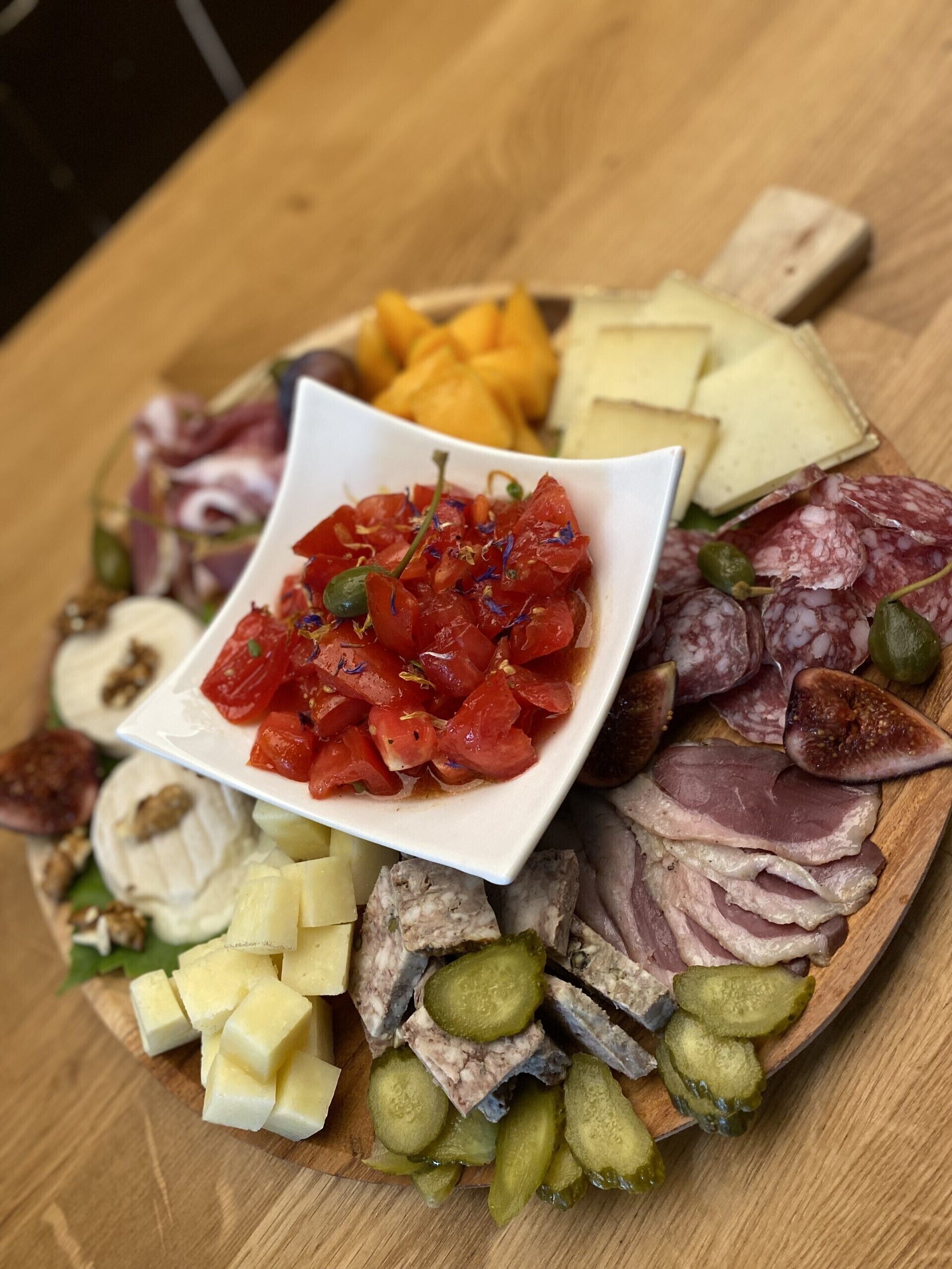 A charcuterie board with various meats, cheeses, and pickles.