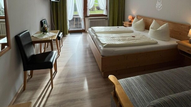 Ein Hotelzimmer mit Bett, Schreibtisch mit Stuhl, Fernseher und Blick ins Freie.