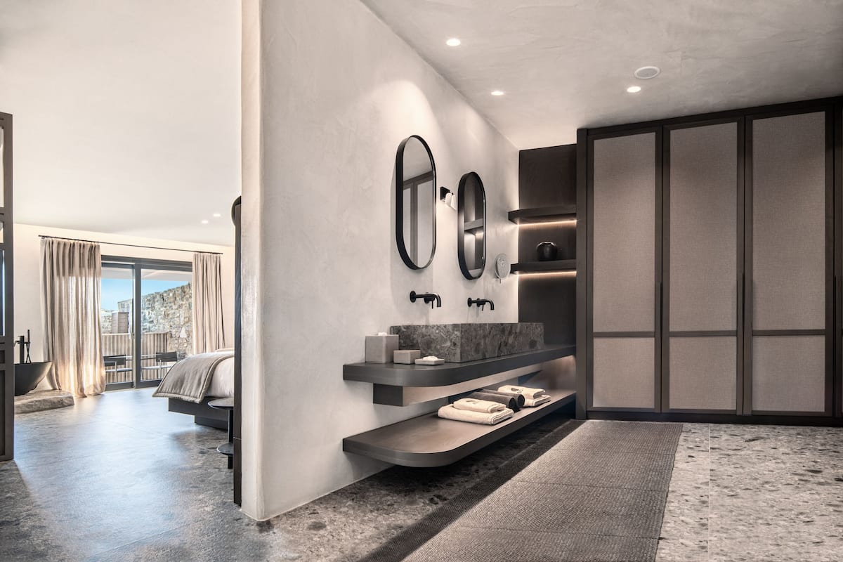 Un baño moderno con un espejo grande, estantes integrados y vistas de la ciudad.