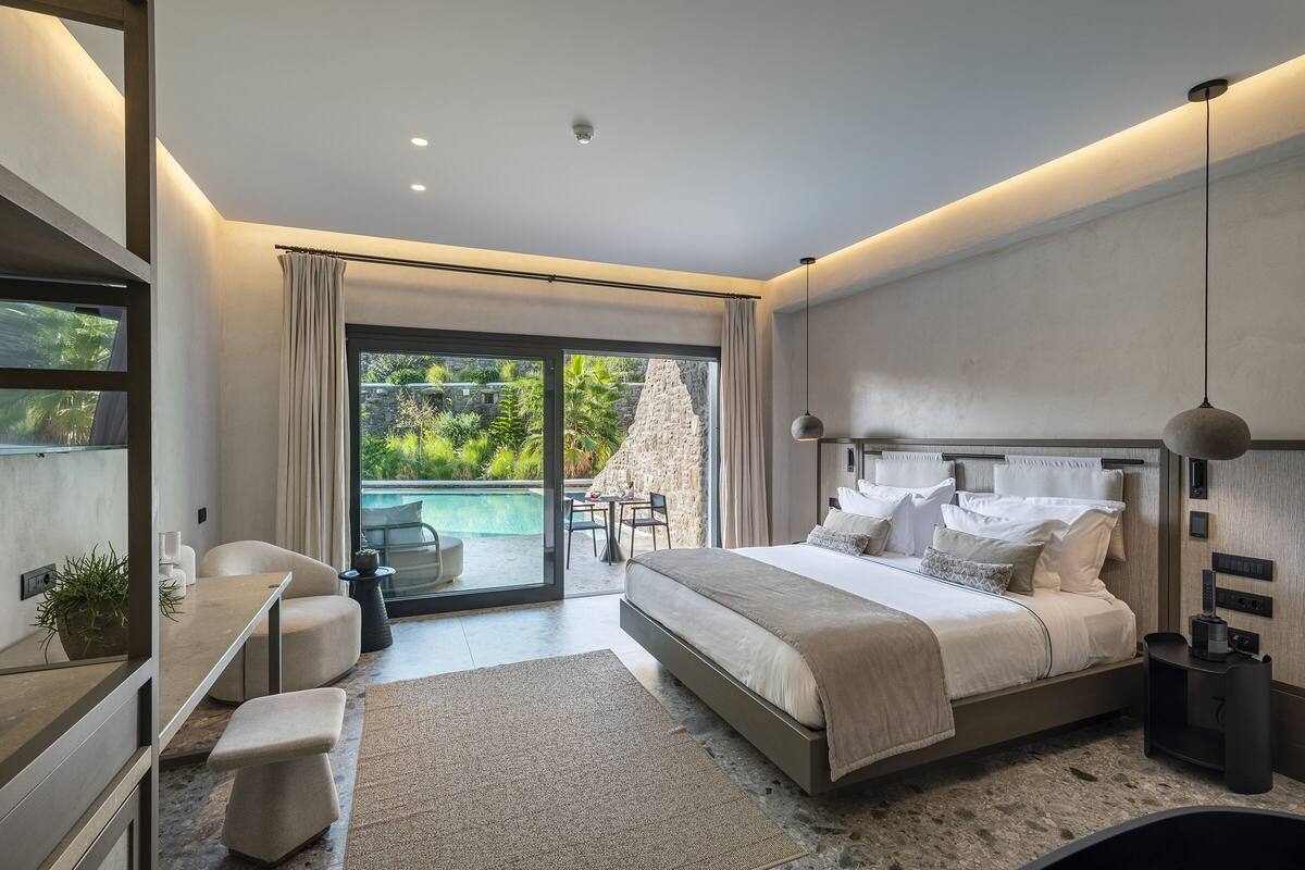 Un dormitorio moderno con una cama grande, un escritorio y vistas a una piscina.