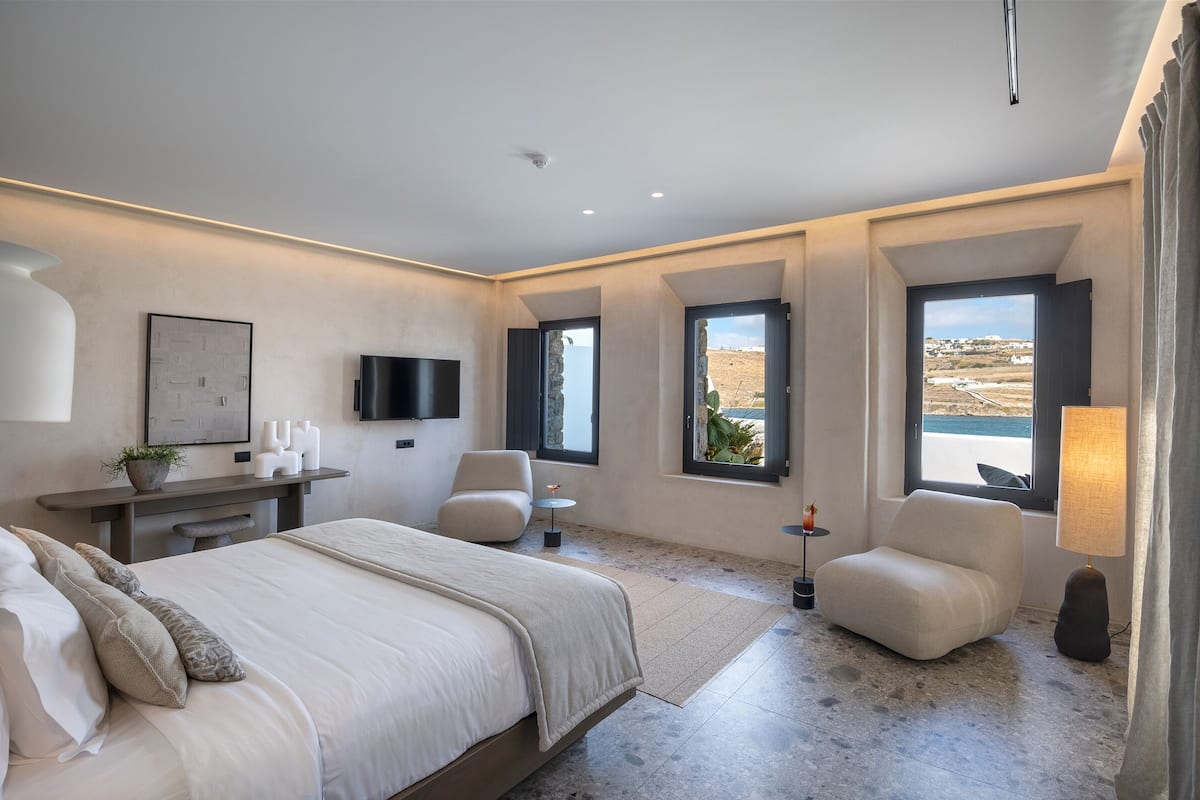 Un dormitorio moderno con una cama grande, un escritorio, una silla y un televisor.