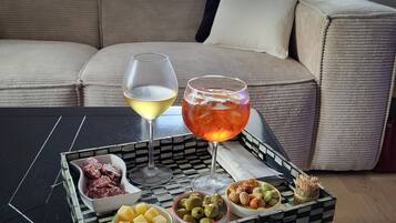 A tray with food and drinks on a table in a living room with a sofa and a window in the background.