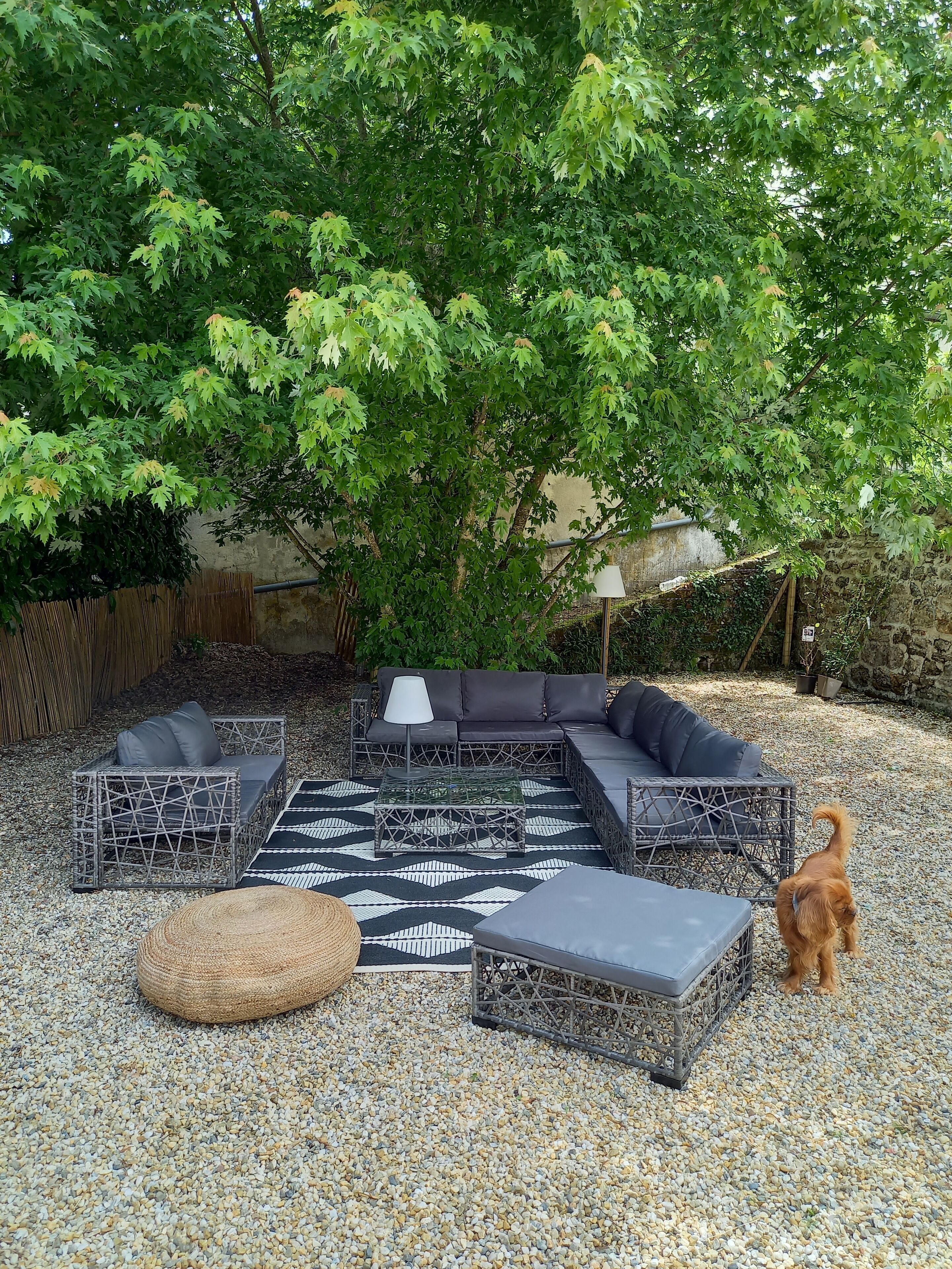 A patio area with a sectional sofa, a coffee table, and a round ottoman.