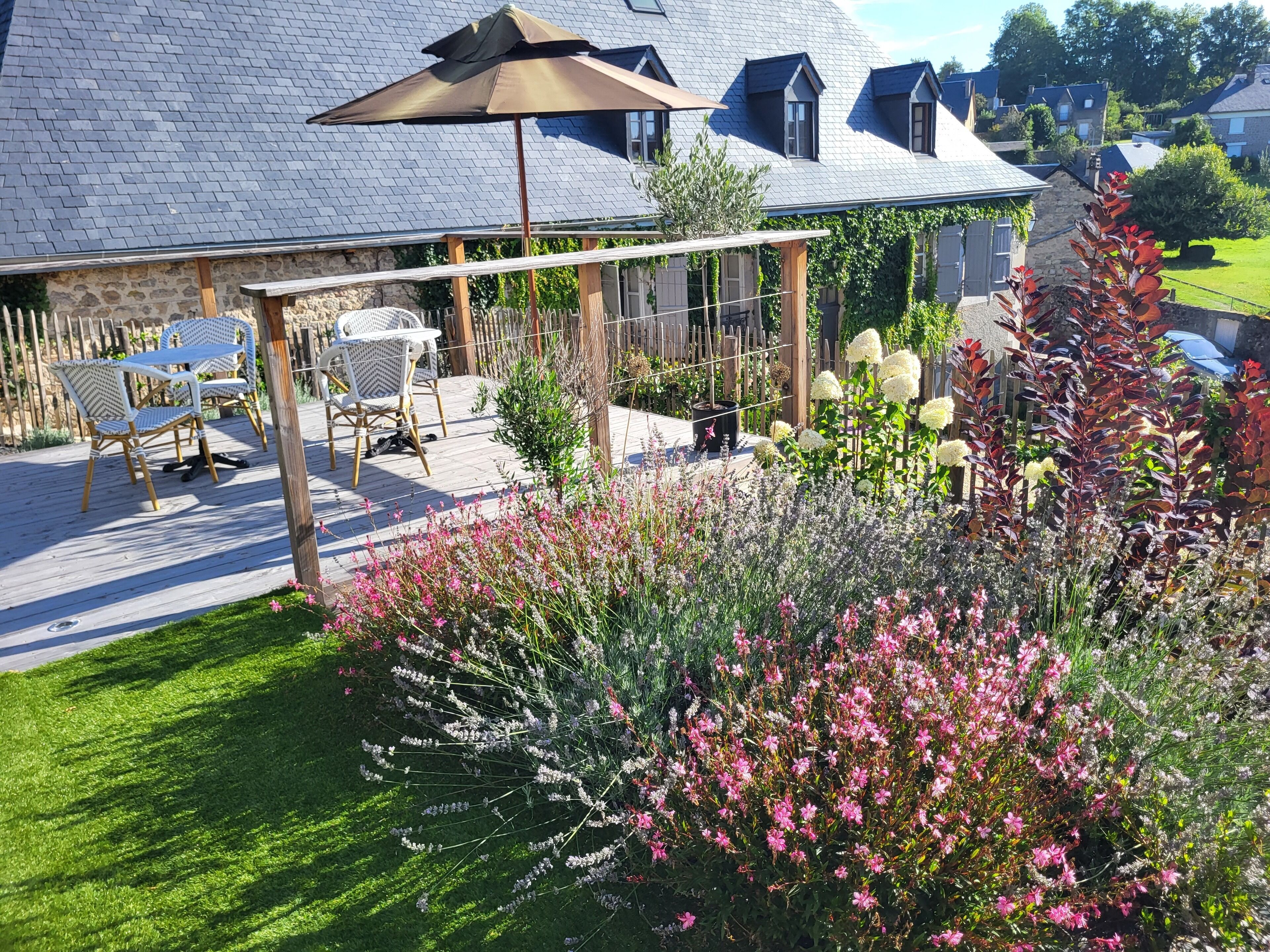 A patio area with outdoor furniture, a pergola, and a garden with various plants and flowers.