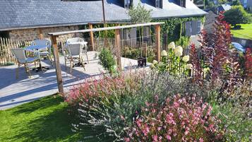 A patio area with outdoor furniture, a pergola, and a garden with various plants and flowers.