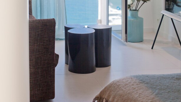 Quarto moderno com vista para o mar, um sofá, uma pequena mesa e um vaso com flores.