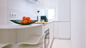 Uma cozinha moderna com armários brancos, bancada curva e uma tigela de laranjas.