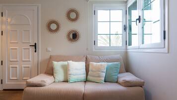 Een woonkamer in neutrale tinten met een beige bank, twee ramen en decoratieve wanddecoratie.