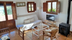 A cozy room with a bed, a TV, a fireplace, and a dining area. - Casa Montecote Eco Resort - Apartment Romero (VEJER)