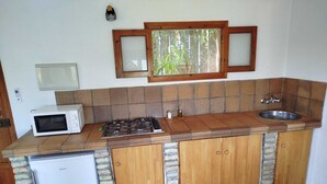 A compact kitchen with a built-in refrigerator, a microwave, a gas stove, and a sink. - Casa Montecote Eco Resort - Apartment Romero (VEJER)
