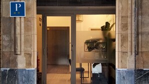 A building entrance with a stone archway, a blue parking sign, and a glass door with a sign reading "AmaBac". - Pensión Ama Bilbao (Bilbao)