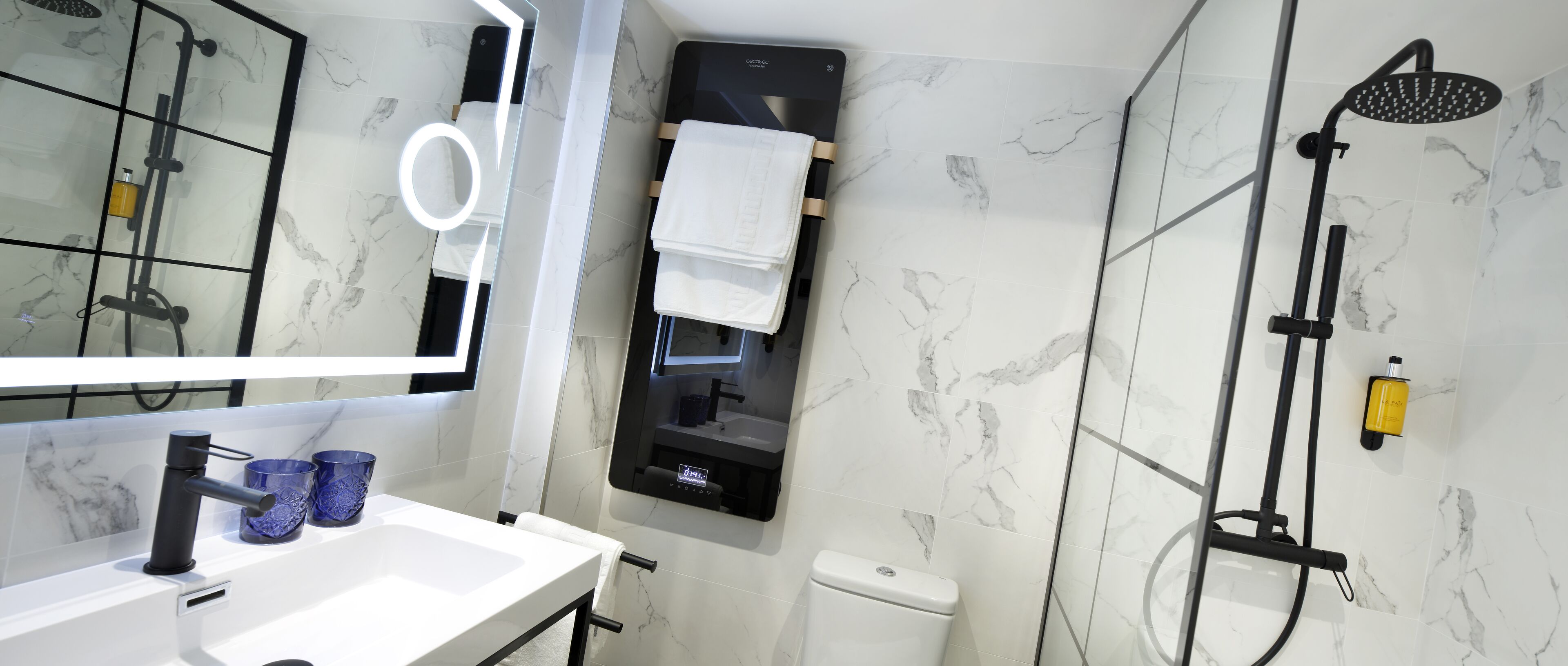 Un baño moderno con un lavamanos blanco, grifo negro y un espejo con luz circular.