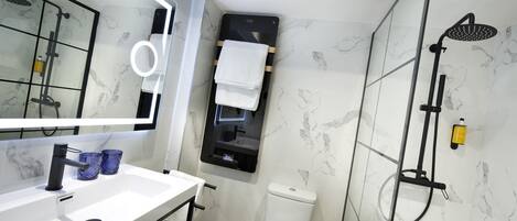 Un baño moderno con un lavamanos blanco, grifo negro y un espejo con luz circular.
