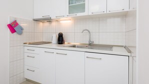 A modern kitchen with white cabinets, a stainless steel sink, and a coffee maker.