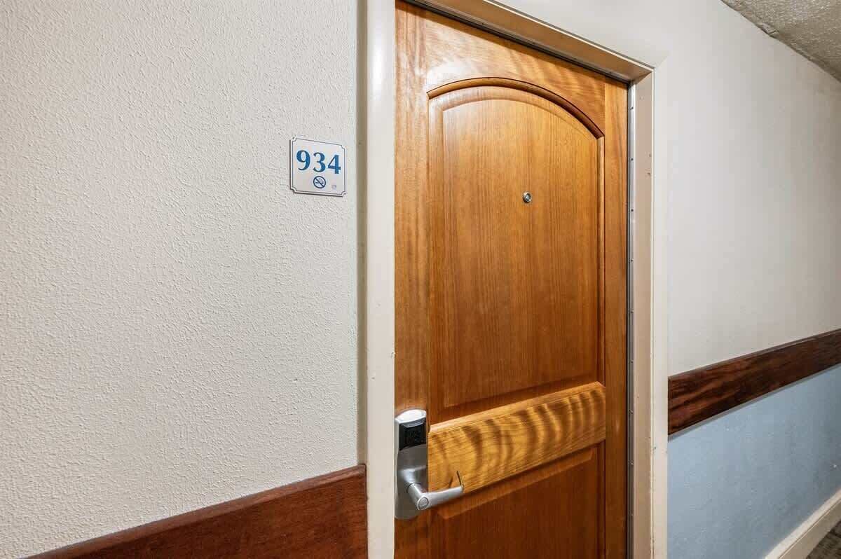 Una puerta de madera con picaporte de latón y un cartelito arriba que indica el número de habitación 934.