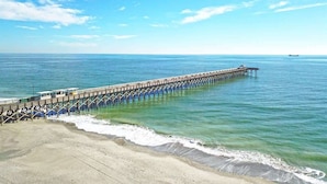 A pier extending into calm waters with a clear sky.