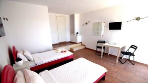 Quarto com duas camas, uma escrivaninha, uma cadeira, uma televisão e uma escada.