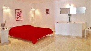 Une chambre à coucher avec un lit, des tables de chevet, une commode et un miroir.