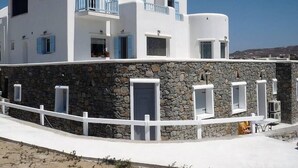 Un bâtiment blanc avec des volets bleus, des murs en pierre et une clôture blanche.