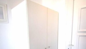 Ein Zimmer mit einem weißen Kleiderschrank, einer Bank und einer Tür.