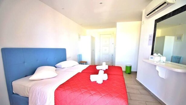 Ein Hotelzimmer mit Bett, Spiegel, Fenster und Klimaanlage.