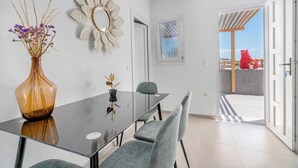 Uma sala de jantar moderna com mesa de vidro, cadeiras cinzentas e vasos decorativos.