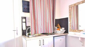 A compact kitchen with a sink, a dishwasher, and a mirror above the countertop. - Large studio apartment for 4 people, in a very (Mikonos)