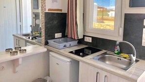A compact kitchen with a built-in stove, a sink, a small dishwasher, and a window with a view of the outside. - Apartment for 4 people, located in Vrysi area, (Mikonos)