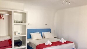 A bedroom with a bed, a wardrobe, and a shelf unit. - Apartment for 4 people, located in Vrysi area, (Mikonos)