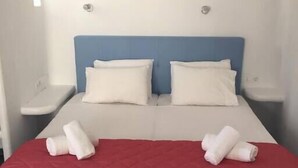 A double bed with white linens, a red bedspread, and two rolled towels. - Apartment for 4 people, located in Vrysi area, (Mikonos)
