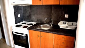 A kitchen with a stove, sink, and wooden cabinets. - Fantastic two-room apartment for 4 people, with (Mikonos)