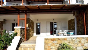 A two-story building with a stone facade, a wooden pergola over the entrance, and a small outdoor seating area with white furniture. - Fantastic two-room apartment for 4 people, with (Mikonos)