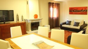 A living room with a fireplace, a television, a dining table, and a sofa. - Villa 315 Fully Renovated Typical Stone House (Barcelos)
