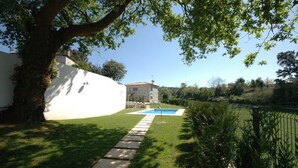A backyard with a swimming pool, a stone pathway, and a white wall. - Villa 315 Fully Renovated Typical Stone House (Barcelos)