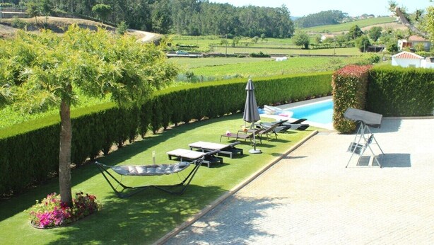 A poolside area with lounge chairs, a hammock, and a view of a lush landscape. - Villa 315 Fully Renovated Typical Stone House (Barcelos)