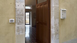 A doorway leading to a room with a wooden door, a small electrical box on the wall, and a tiled floor. - Old town Modica - newly renovated family home (Modica)