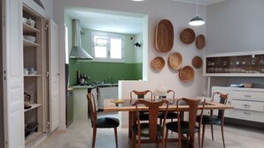 A dining area with a wooden table and chairs, a kitchen in the background, and decorative plates on the wall. - Old town Modica - newly renovated family home (Modica)