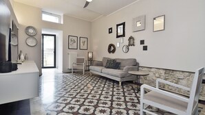A modern living room with a patterned floor, a sofa, a chair, and a small table. - Old town Modica - newly renovated family home (Modica)