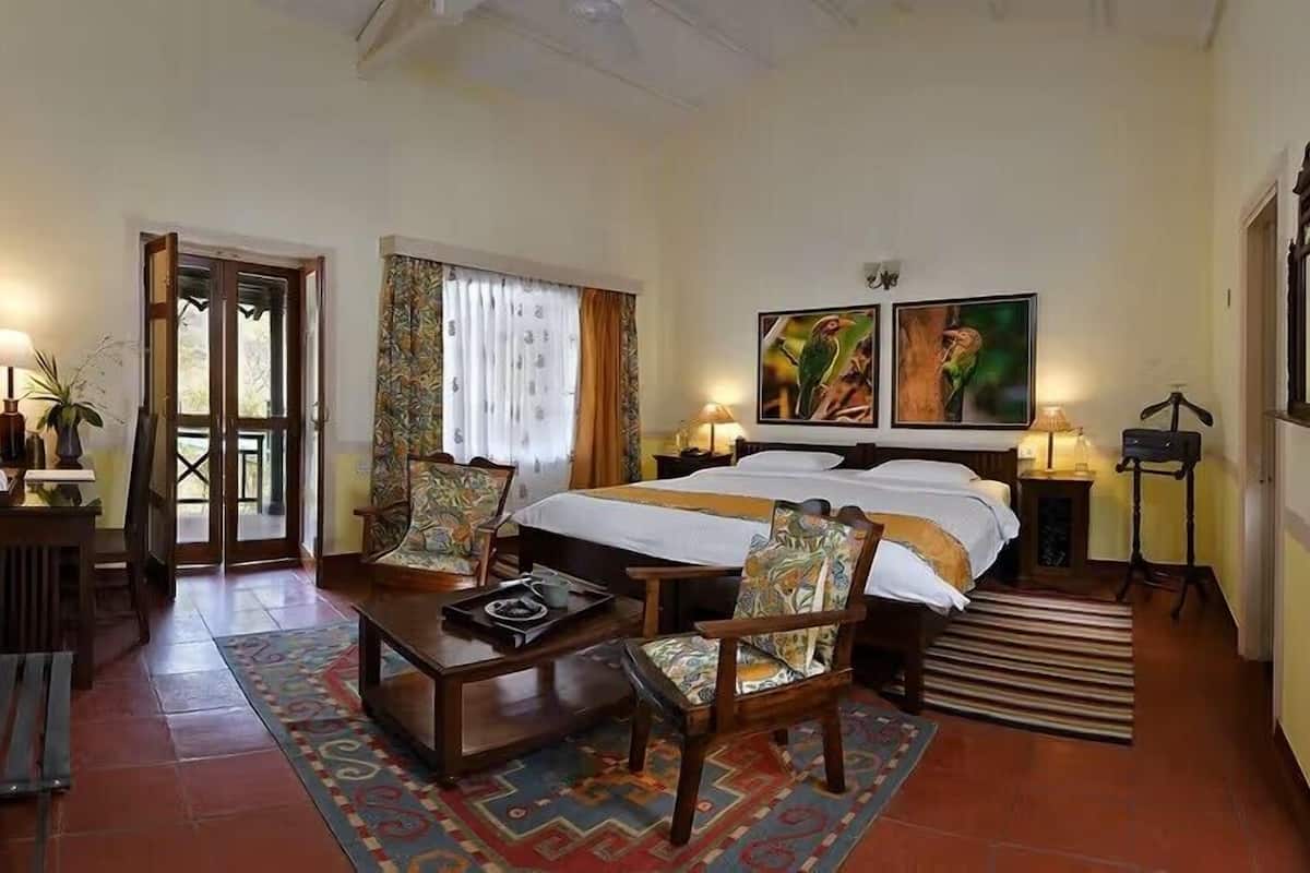 A bedroom with a bed, two chairs, a small table, a radiator, and a door leading outside.