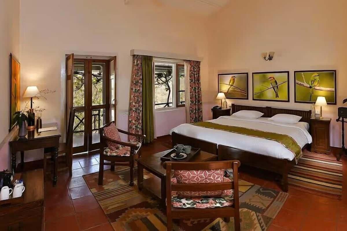 A bedroom with a bed, a chair, a table, a lamp, and a window.