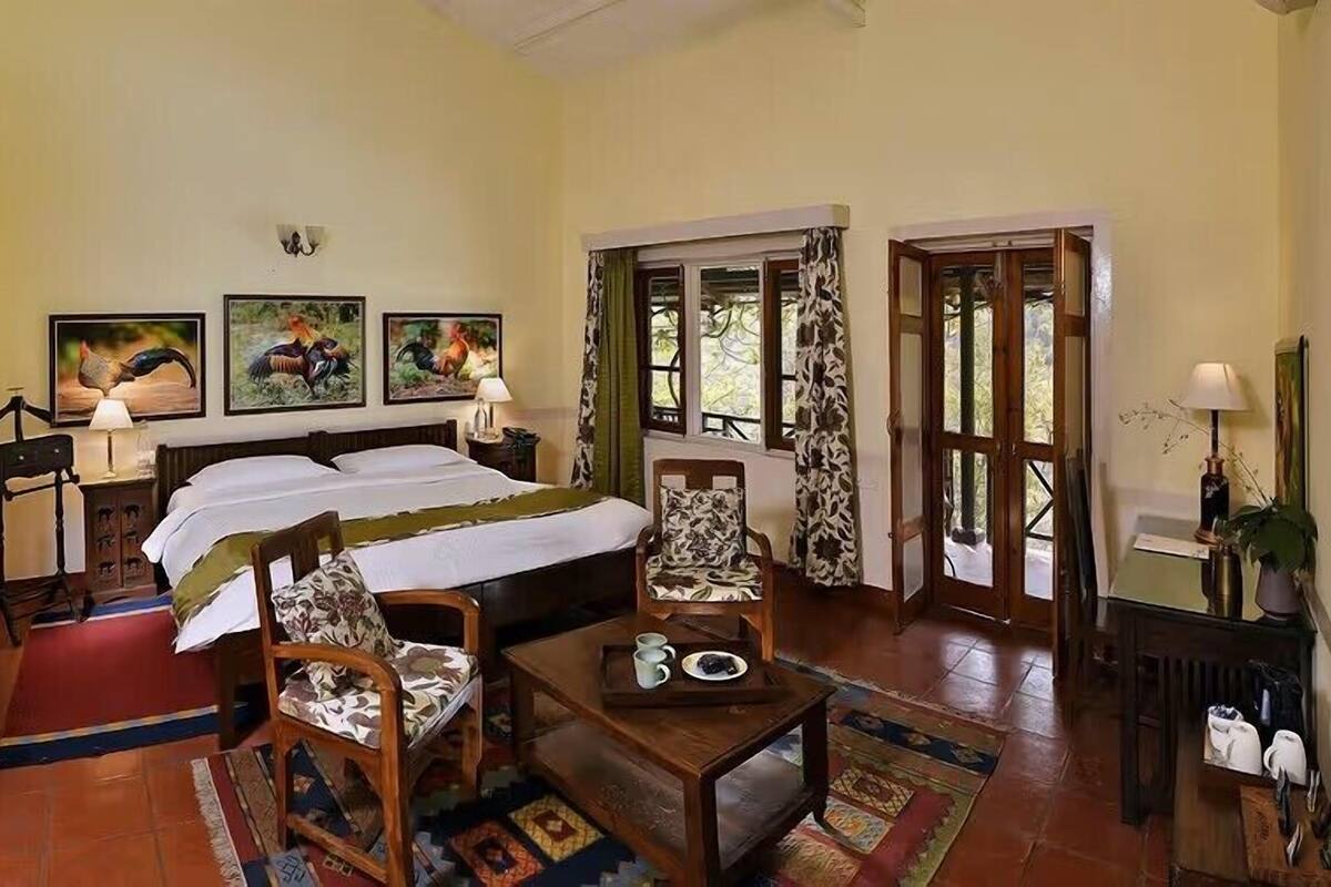 A hotel room with a bed, two chairs, a table, a mirror, and artwork on the walls.
