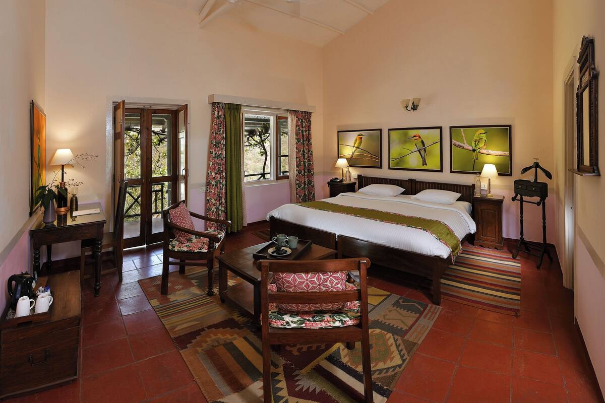 A bedroom with a bed, two bedside tables, a chair, a desk, and a window with curtains.