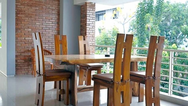 Un comedor con pared de ladrillo, sillas de madera y una mesa.